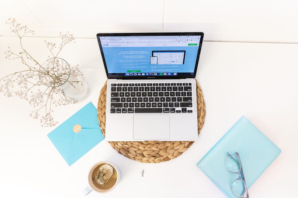 Flat lay of a MacBook showing the NN Accountability Xero training site, beside a business planner, glasses and tea